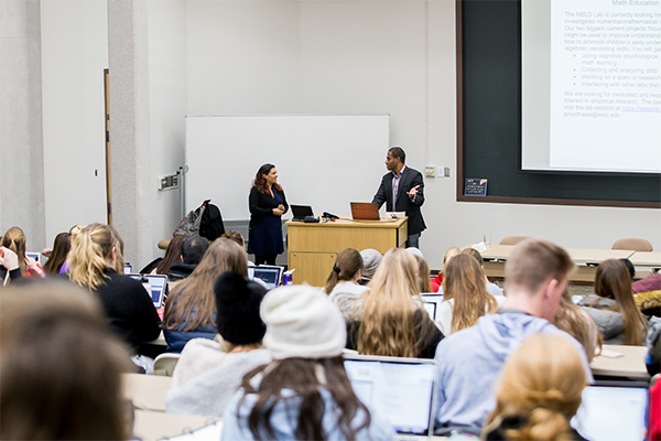 classroom showing students and lecturers at the front of a large lecture hall